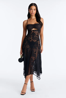 Elegant woman in black lace midi dress with cutout and asymmetrical hem.