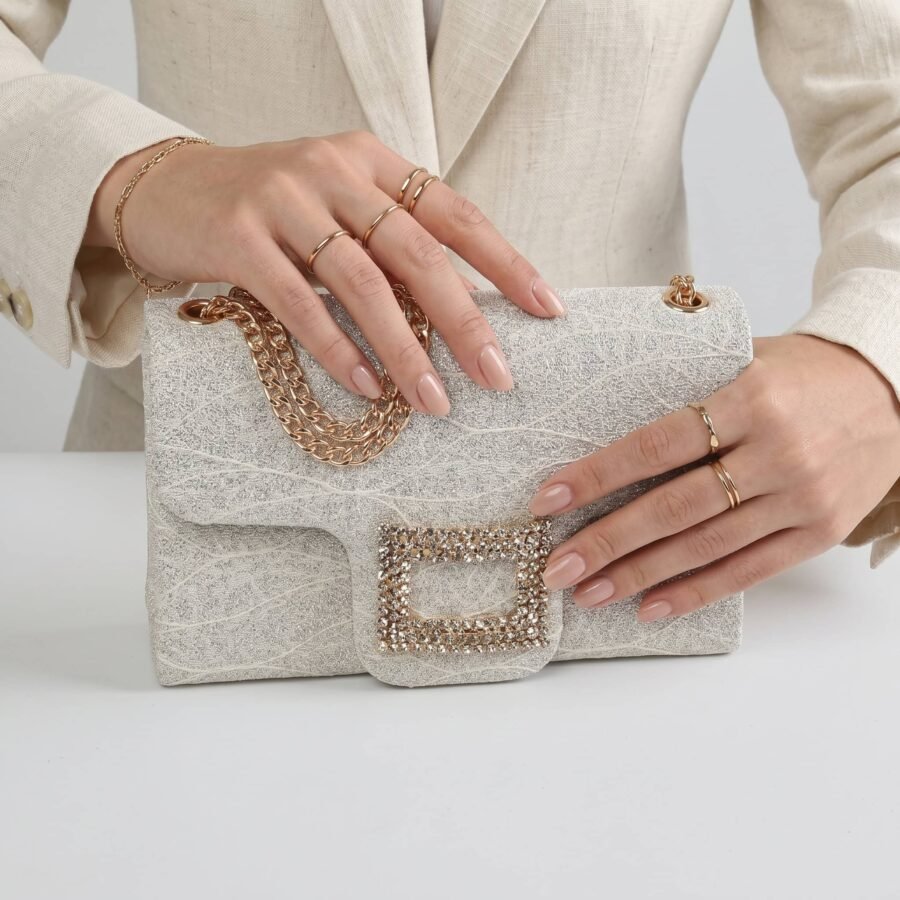 Sac à main en tissu brillant avec chaîne dorée et détails en strass..